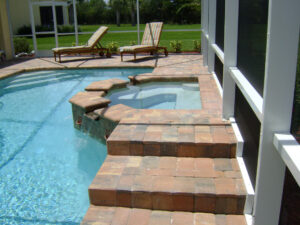 Pool with brick steps, hot tub, and sun loungers