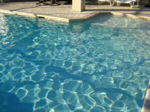 Clear rippled pool water with a sunlit deck