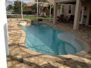 Curvy pool with a stone deck and a lake view