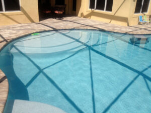 Curved pool with shadow play on water and patio chairs